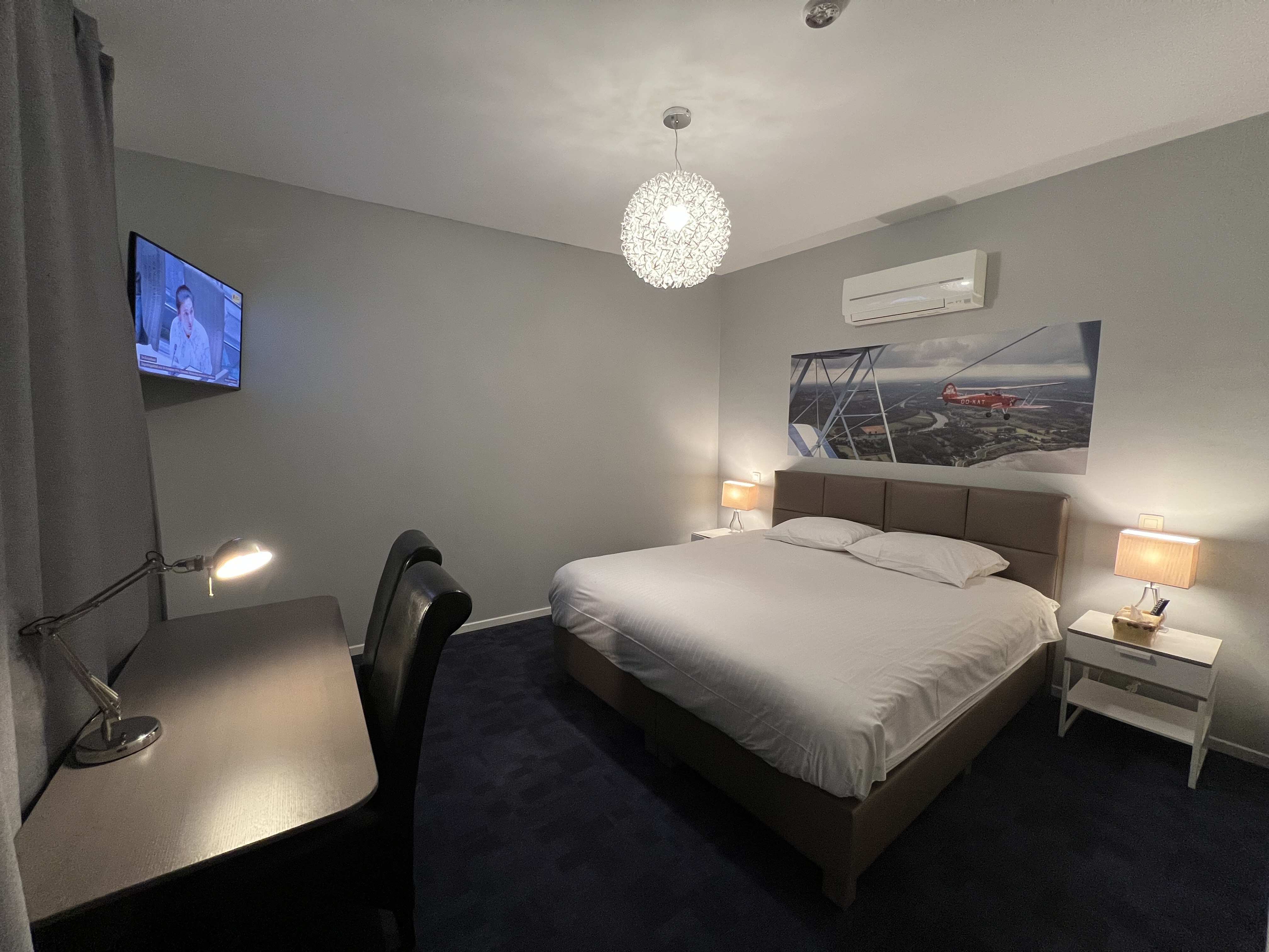 deluxe hotel suite bedroom with king bed, modern furniture, city view, elegant lighting