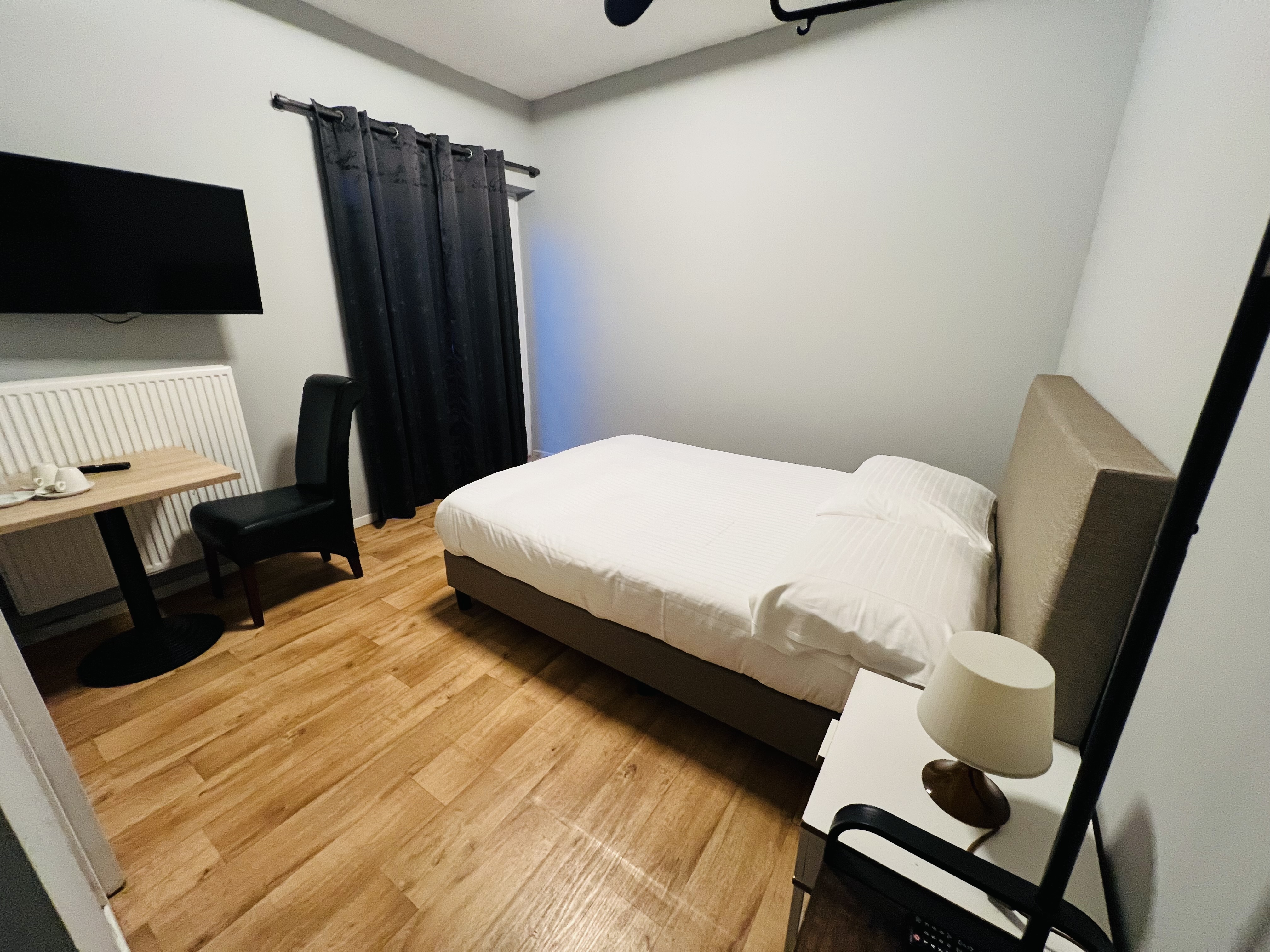 deluxe hotel suite bedroom with king bed, modern furniture, city view, elegant lighting