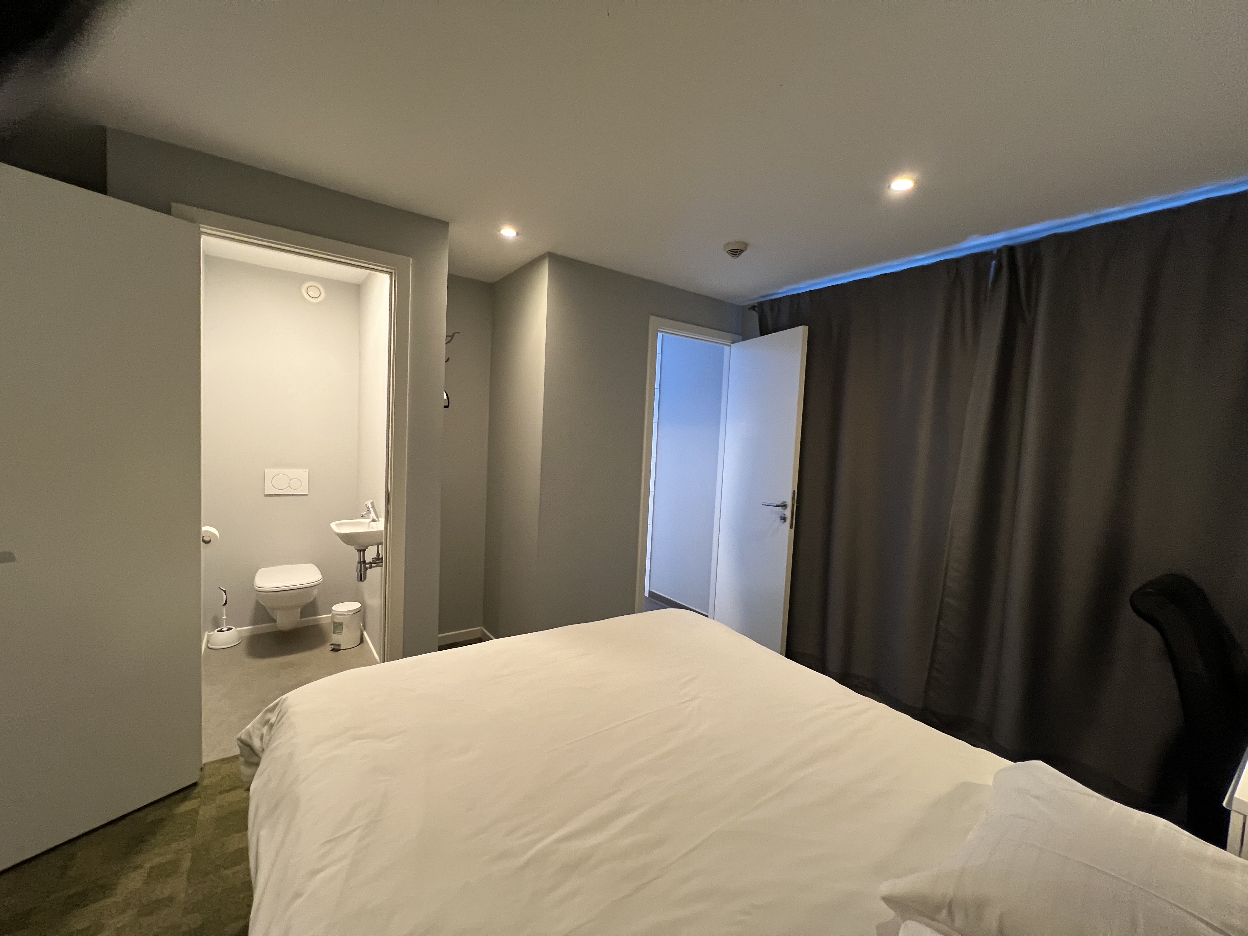 deluxe hotel suite bedroom with king bed, modern furniture, city view, elegant lighting